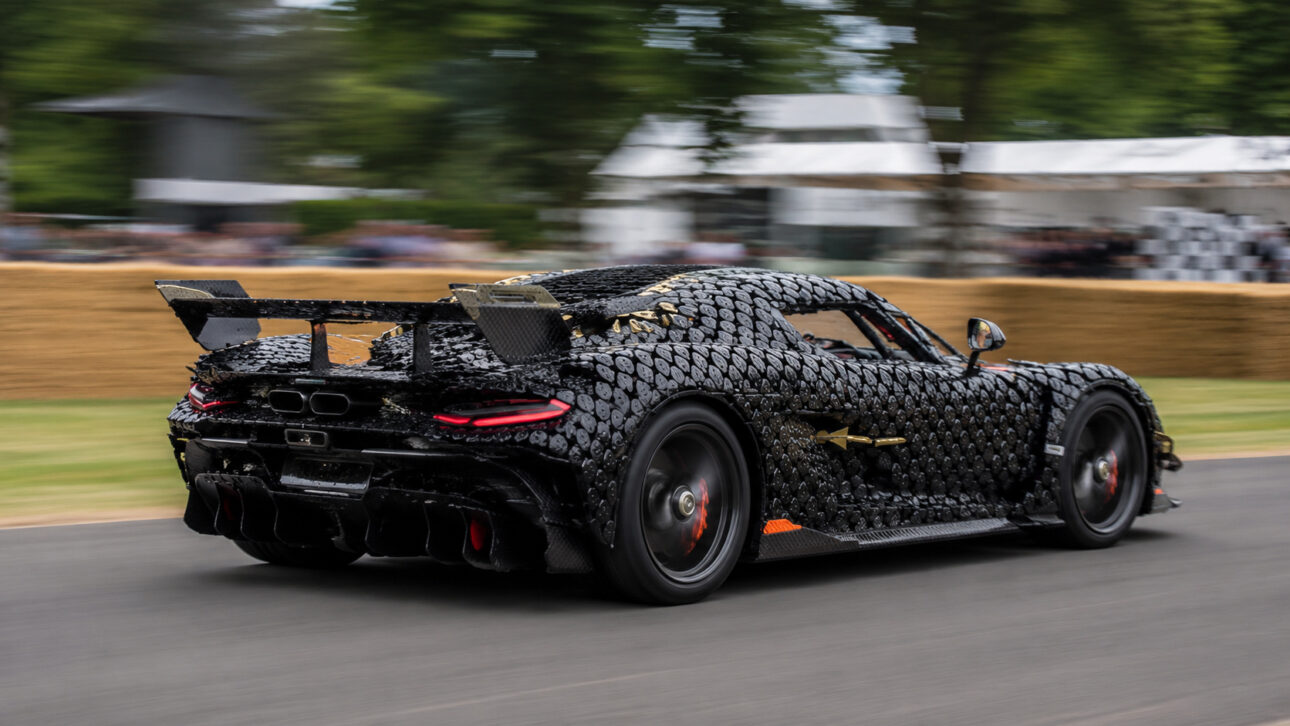 Black supercar with stylized bodywork moving quickly on a track, with a blurred background and automotive event atmosphere.
