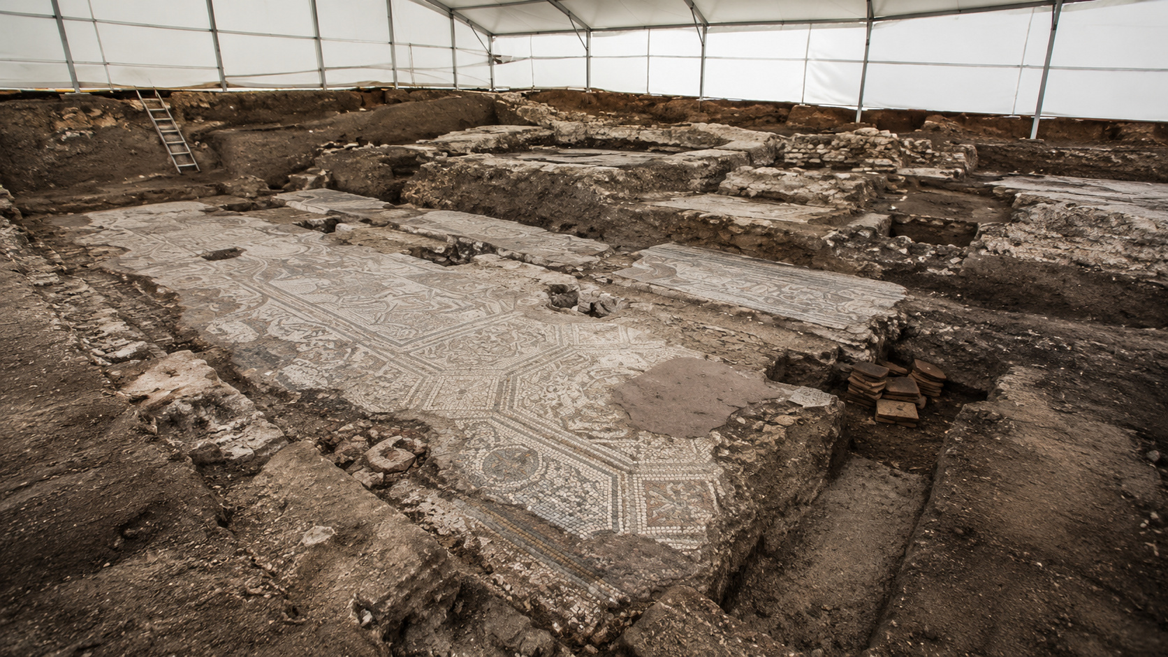 Escavação arqueológica com mosaicos antigos e fundações de igreja de 1.600 anos sob tenda de proteção em Oderzo, na Itália.