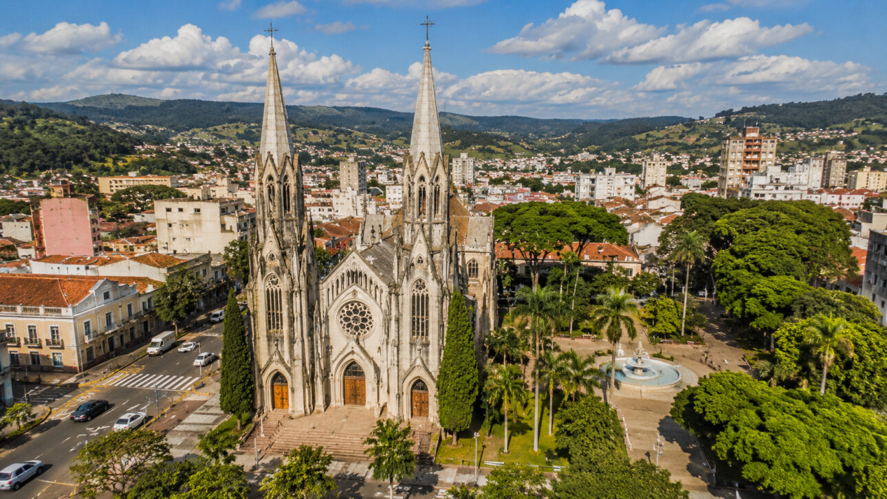 Historic church in Botucatu seen from above, surrounded by a square, trees, streets, and green landscapes of the Cuesta Paulista.