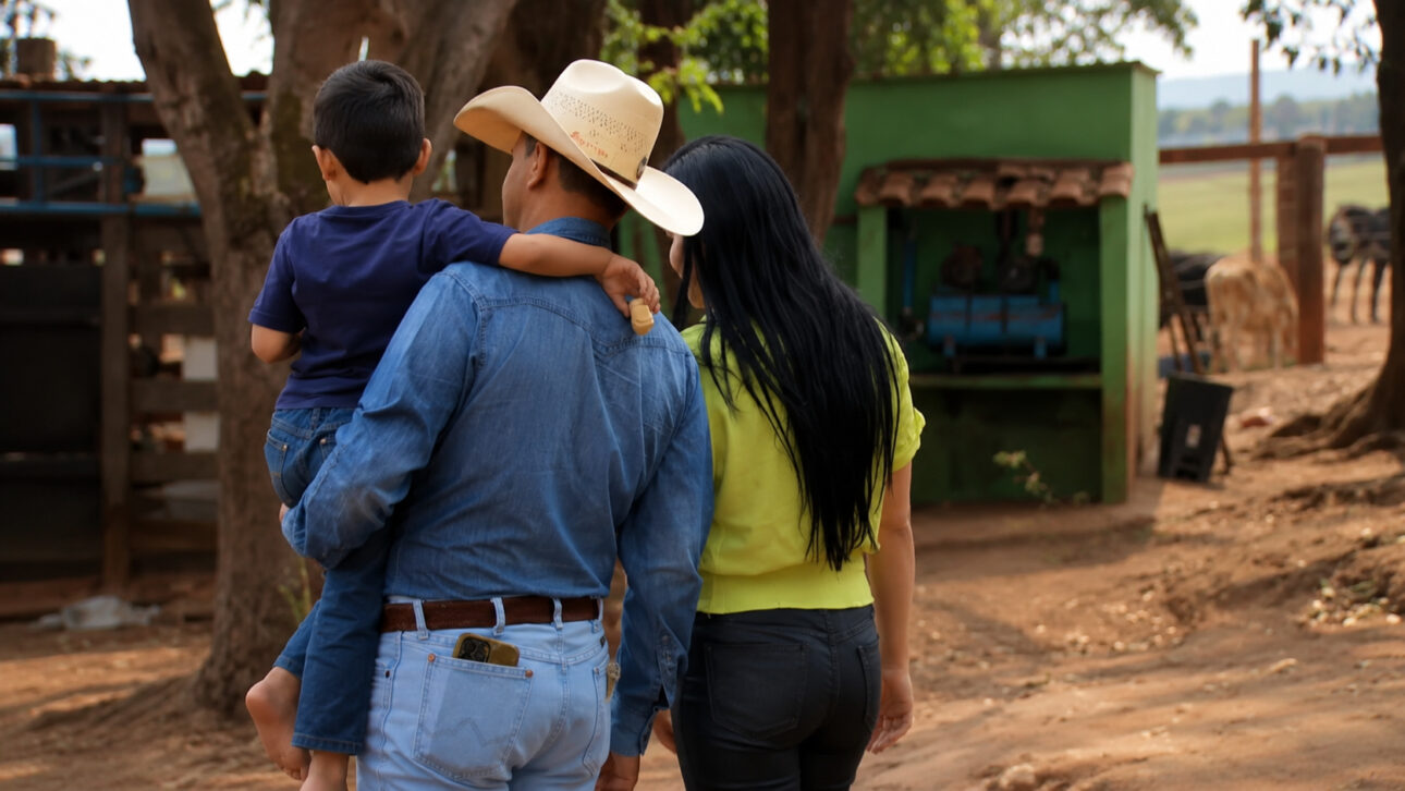 Man carrying a child next to a woman on a dirt ranch road, symbolizing the family bond in the DNA test case.