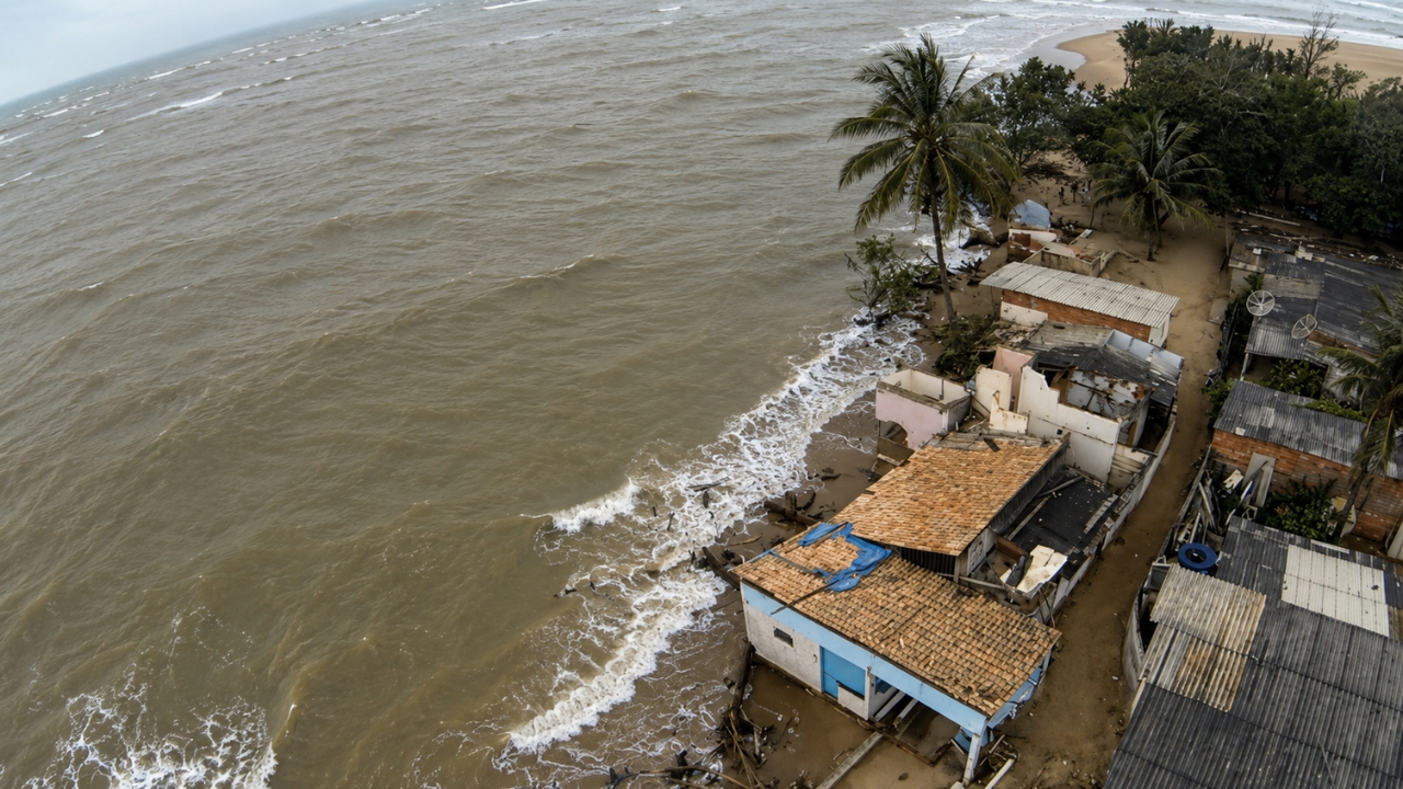 Imagem aérea mostra casas encurraladas pelo avanço do mar em Atafona, no litoral do Rio de Janeiro, onde a erosão costeira aproxima as ondas das construções e transforma antigas áreas urbanas em cenário de risco permanente.