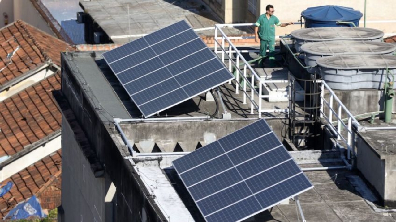 Painéis solares instalados em telhado urbano simbolizam o avanço da geração própria no Brasil, que já soma milhões de sistemas conectados e começa a pressionar redes elétricas em estados como Mato Grosso, Acre e Rondônia, onde novas conexões enfrentam restrições técnicas por excesso de energia injetada no sistema.