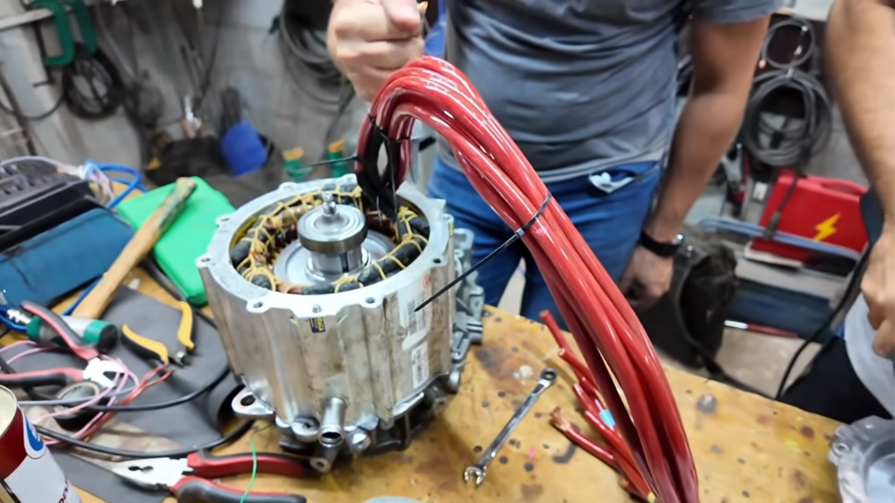 Motor elétrico reaproveitado passa por rebobinagem em bancada, com novos cabos de maior espessura para suportar a corrente mais alta exigida pela adaptação ao câmbio do Fiat Uno. Fonte: canal LetraJota/YouTube.
