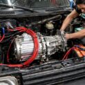Mecânicos adaptam motor elétrico de BYD no câmbio de um Fiat Uno velho, rebobinam o conjunto para trabalhar com baixa tensão e fazem o carro rodar em silêncio, subir ladeira e chegar perto de 60 km/h ainda em teste caseiro