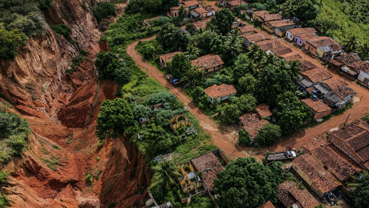 Voçoroca gigante avança em área verde próxima a bairros residenciais no Nordeste brasileiro, mostrando a dimensão da erosão que ameaça casas, ruas e moradores em áreas de risco.