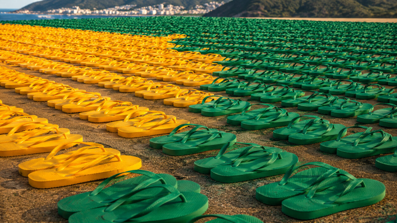 Milhares de chinelos verdes e amarelos organizados em fileiras, formando um mosaico inspirado na bandeira do Brasil para ação da Havaianas na Copa de 2026.
