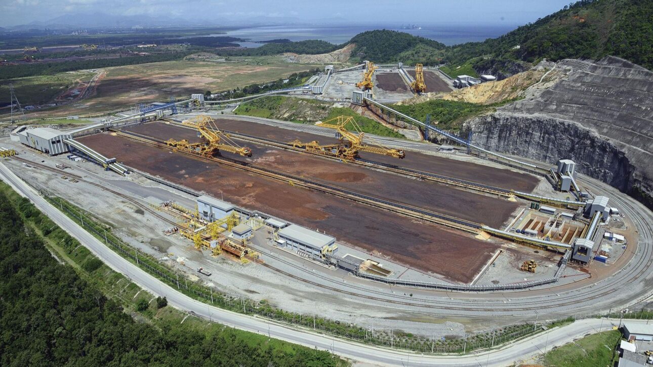 Máquinas gigantes no Porto Sudeste movem minério de ferro entre vagões, correias e navios em Itaguaí, com operação de 12.000 t/h real.