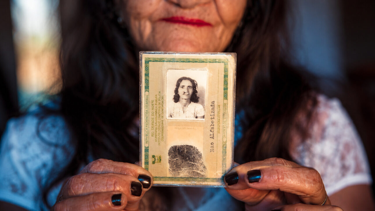 Idosa segura documento antigo com foto, representando sua história antes da cirurgia de lábio leporino no Rio Grande do Norte.