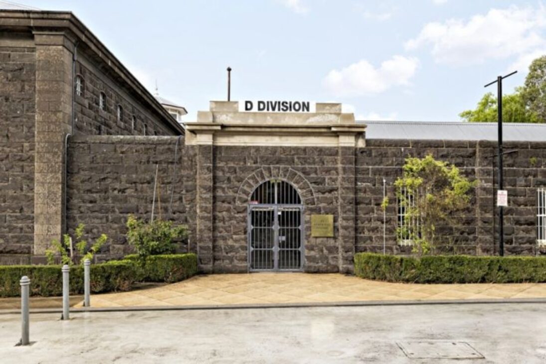 Fachada de pedra da Divisão D da antiga prisão de Pentridge, na Austrália, com entrada central protegida por grades.