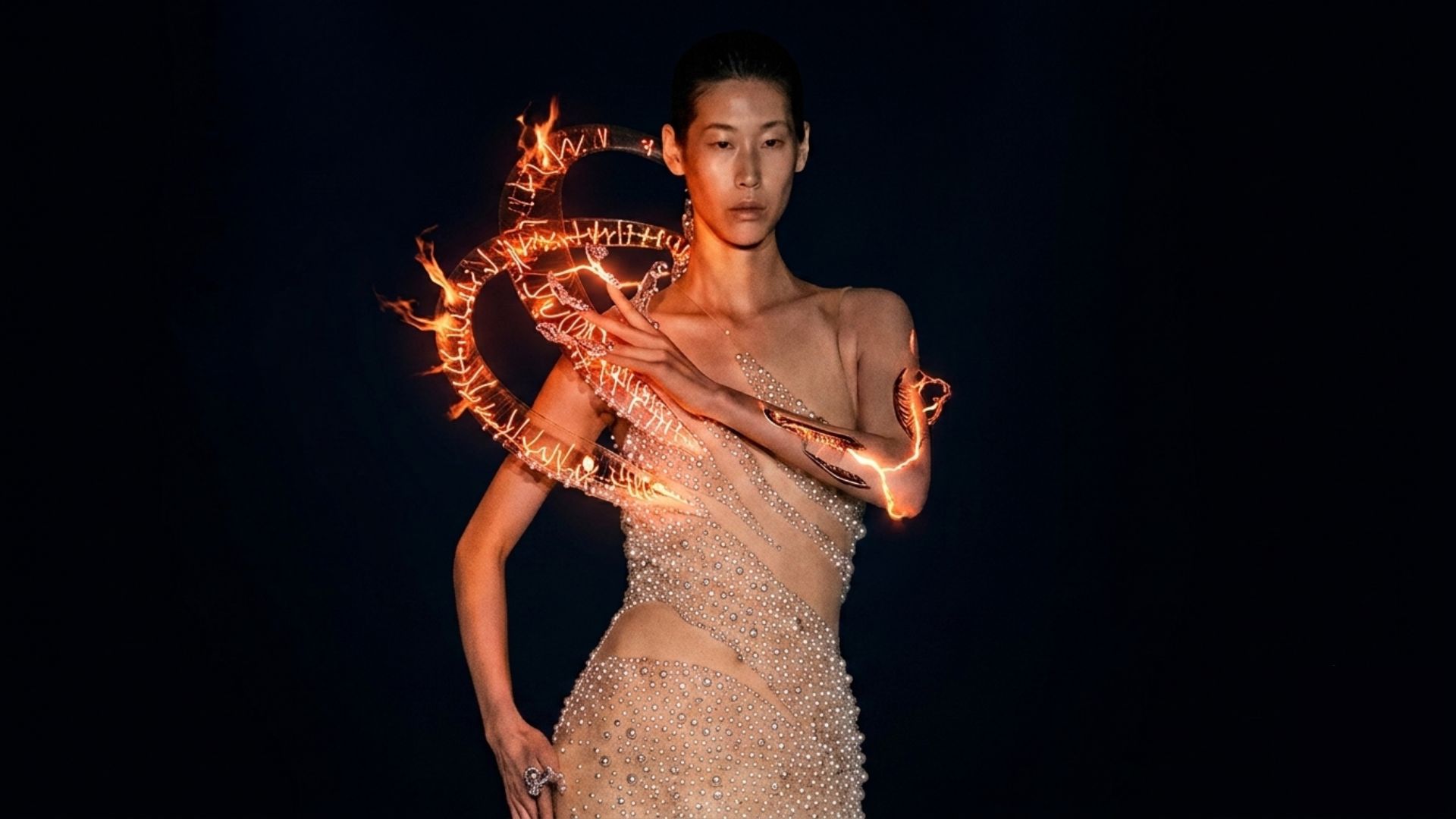 Modelo na passarela vestindo o Helix Nebula de Iris Van Herpen, o primeiro vestido de plasma do mundo, feito com estruturas de vidro soprado iluminadas por descargas elétricas e gases ionizados em fundo escuro.