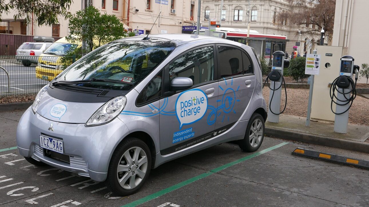 A compact electric car plugged into a charging station, like those installed at highway stations. (Illustrative image)
