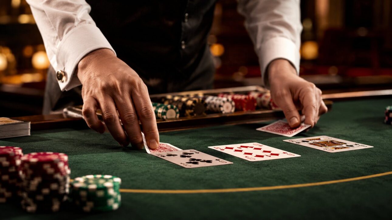 Mesa de cassino com cartas sendo distribuídas sobre o feltro verde