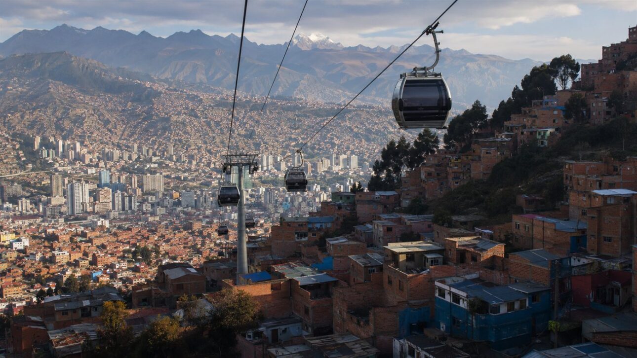 Rede de teleférico urbano cruzando uma cidade cercada de montanhas