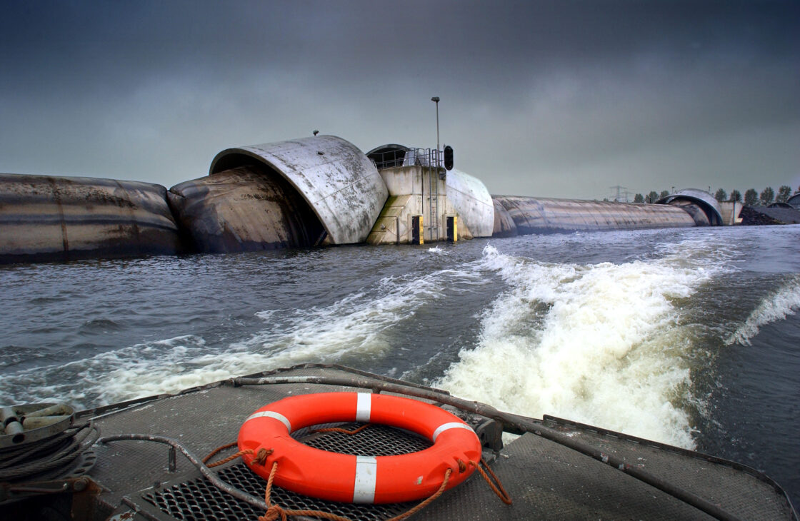 Barreira inflável de Ramspol, na Holanda, aparece erguida sobre o canal após ser preenchida com ar e água; o sistema usa três bolsas de borracha de 80 metros cada, formando uma defesa de cerca de 240 metros de extensão e 10 metros de altura contra a elevação da água durante tempestades. Fonte: Rijkswaterstaat/DMC.