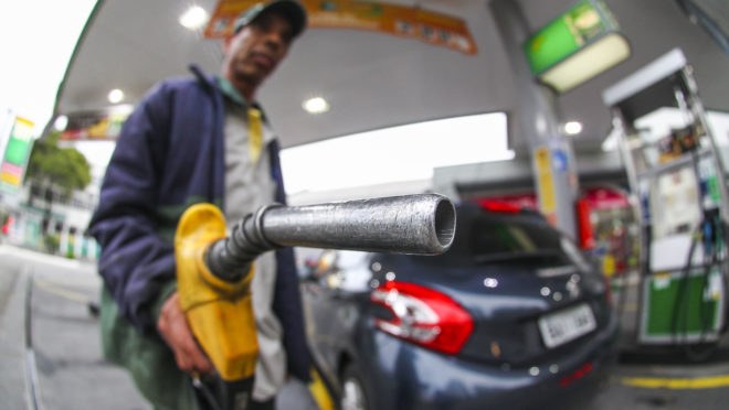 Pessoa abastecendo veículo em posto de combustível
