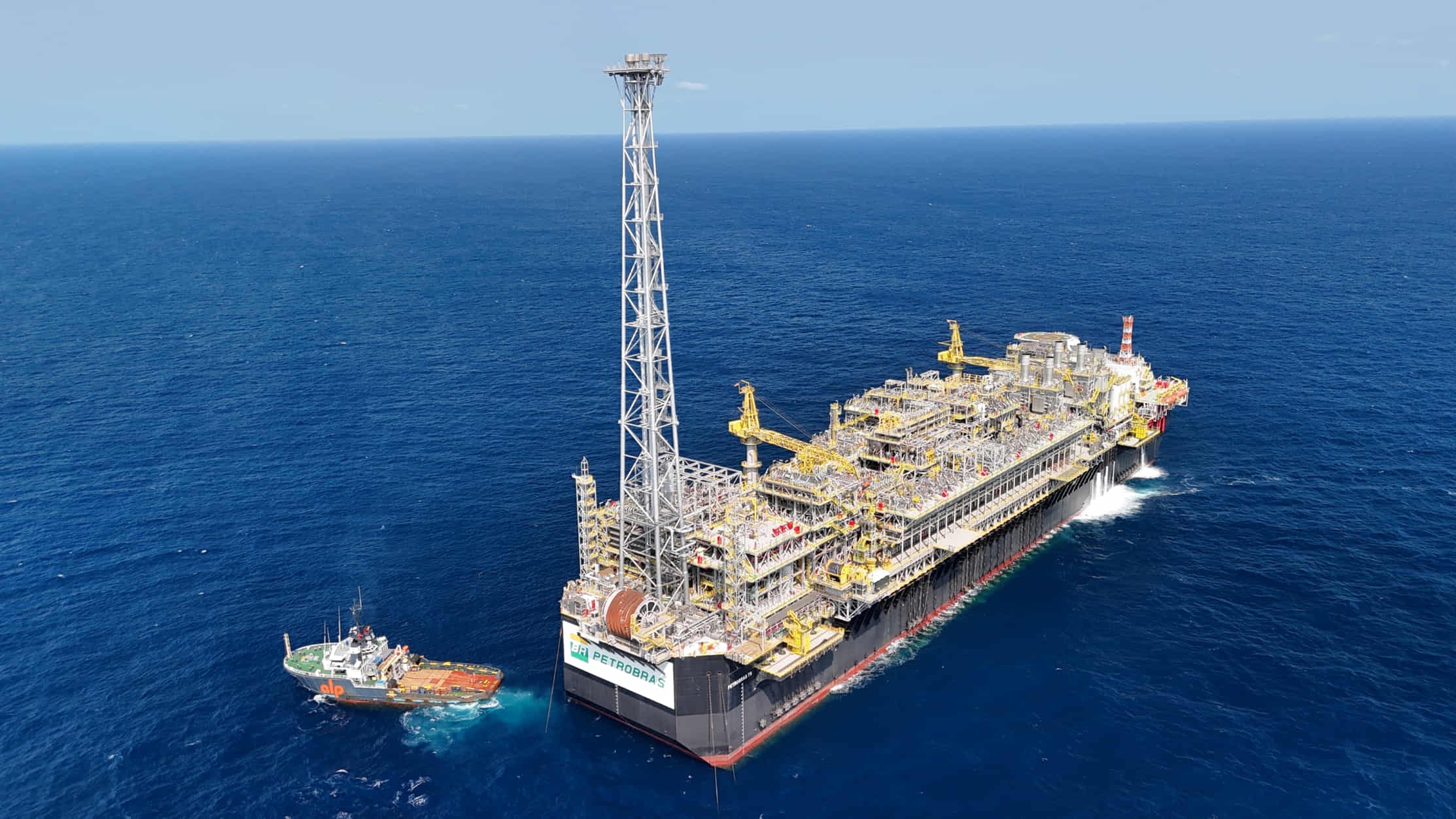 Petrobras FPSO platform operating in open sea with tugboat alongside