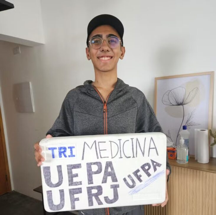 Ítalo Cantanhede segura cartaz com os nomes Uepa, UFRJ e Medicina após conquistar três aprovações em universidades públicas.