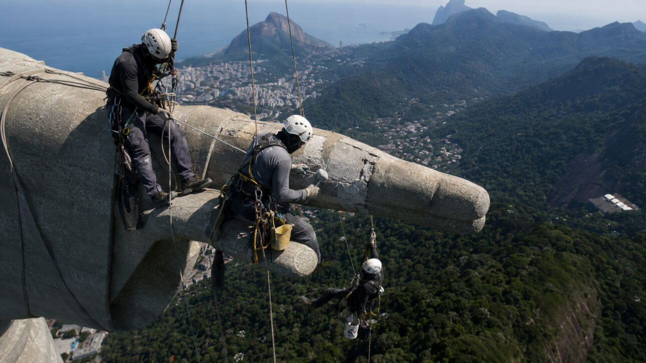 Técnicos realizam manutenção no Cristo Redentor utilizando técnicas de rapel.