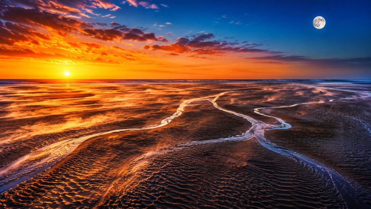 Extensive strip of sand exposed by the retreat of water on the beach, with the sea distant on the horizon.