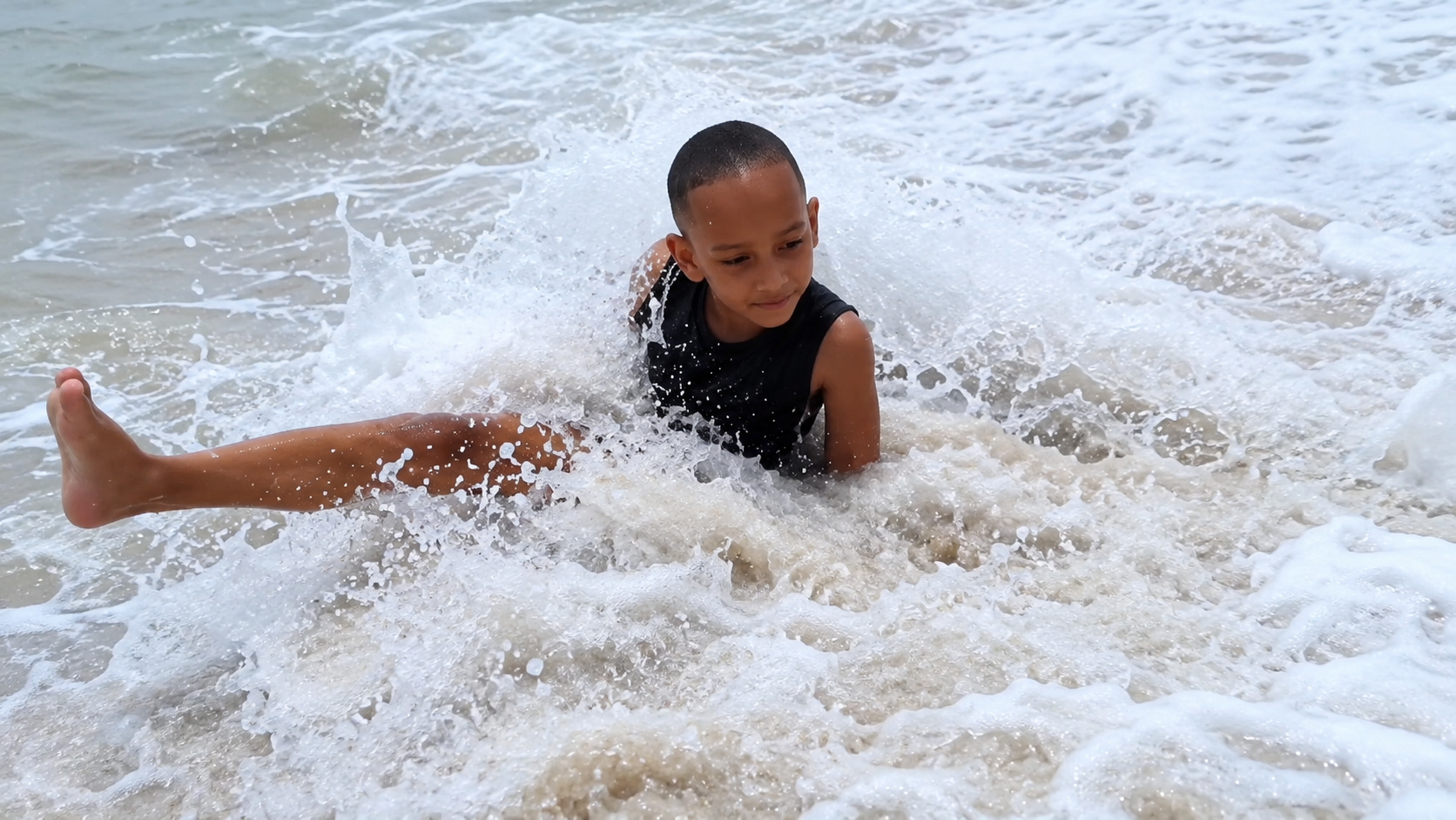 Menino brinca entre as ondas do mar pela primeira vez após iniciar tratamento para controlar a rara urticária aquagênica, conhecida como alergia à água.