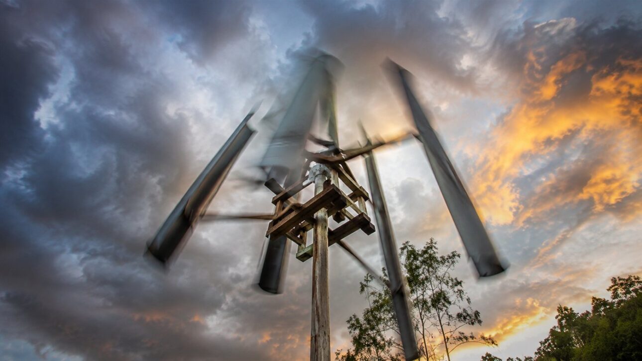 As pás artesanais da turbina giram no alto da torre improvisada perto da casa.