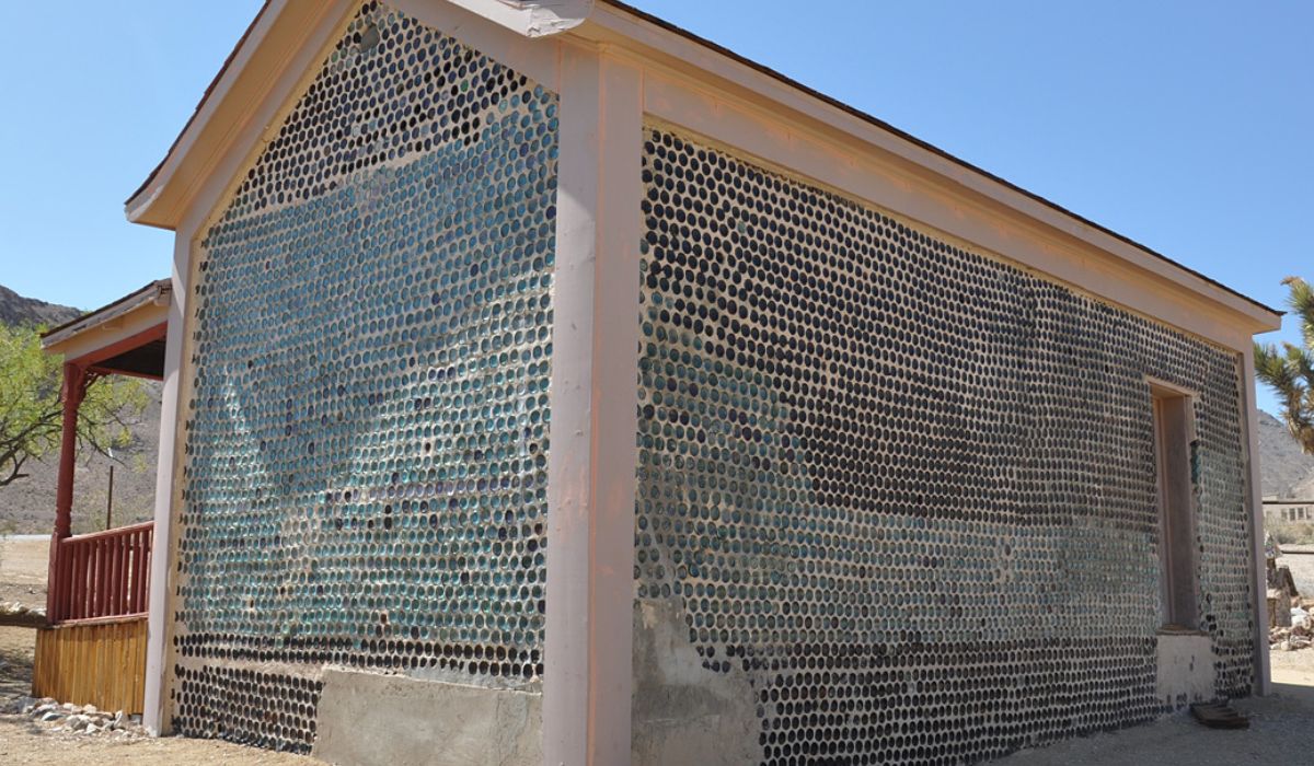 Fachada da Tom Kelly Bottle House mostra milhares de fundos de garrafas incorporados ao adobe, solução adotada em uma região onde materiais tradicionais de construção eram caros. Crédito: Finetooth/Wikimedia Commons