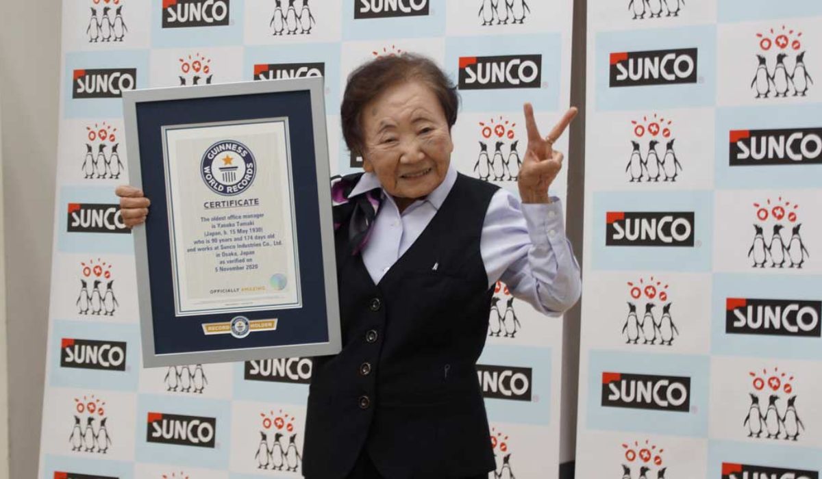 Yasuko Tamaki segura o certificado do Guinness World Records após ser reconhecida como a gerente de escritório mais velha do mundo, aos 90 anos. Crédito: Guinness World Records.