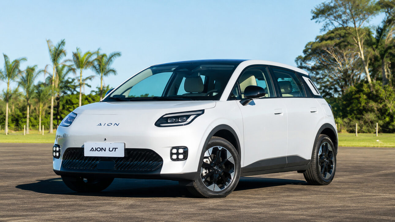 GAC Aion UT branco fotografado em perspectiva frontal lateral sobre pista asfaltada, com árvores ao fundo, representando o modelo elétrico que impulsionou o crescimento da montadora chinesa no mercado brasileiro em julho de 2026.
