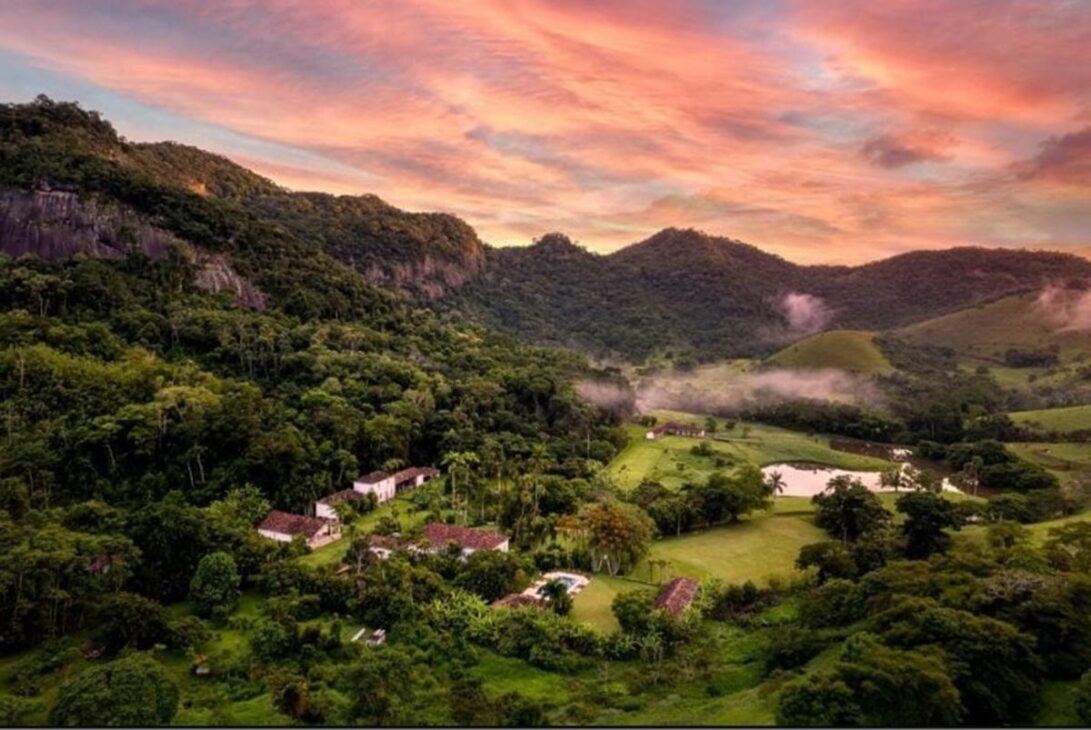 Vista aérea da fazenda de Lenny Kravitz entre montanhas, áreas verdes, lagos e construções rurais em Duas Barras.