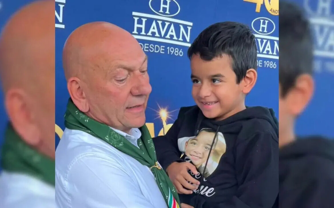Luciano Hang segura Henrique durante encontro na inauguração da Havan em Taquara, no Rio Grande do Sul.