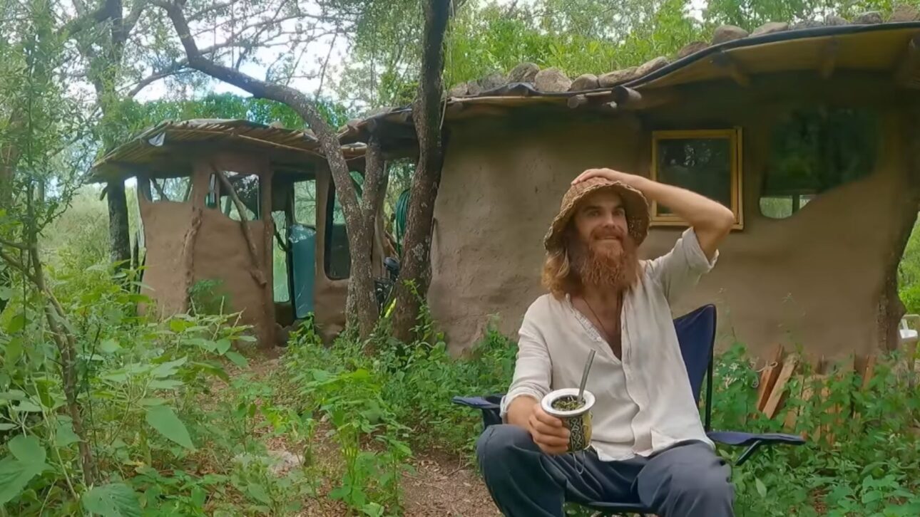Mago caminhando pela mata nativa da Serra de Córdoba ao lado de sua casa de barro construída por bioconstrução.