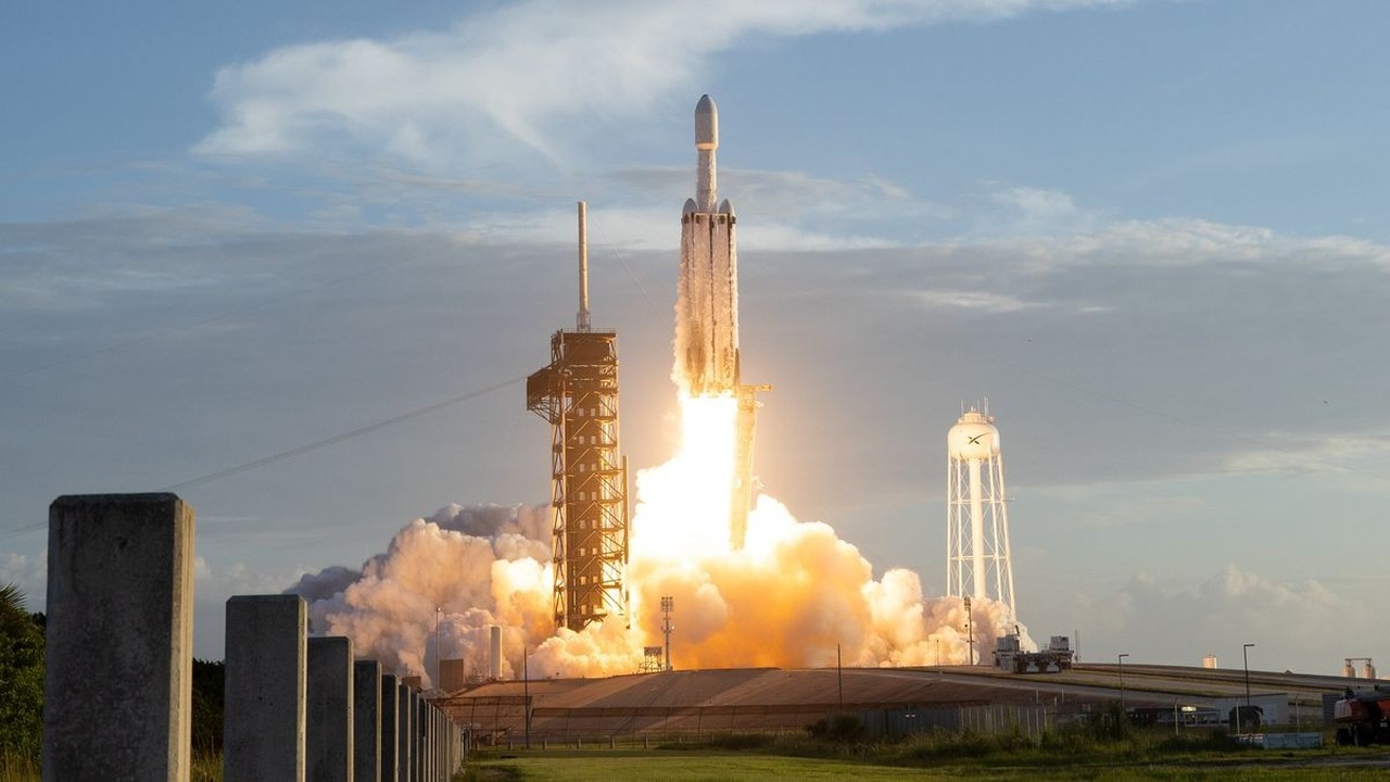 Foguete Falcon Heavy decola de uma plataforma de lançamento envolto em chamas e fumaça