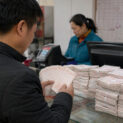 Apostador chinês confere milhares de bilhetes comprados com os mesmos sete números em uma lotérica de Nanchang.