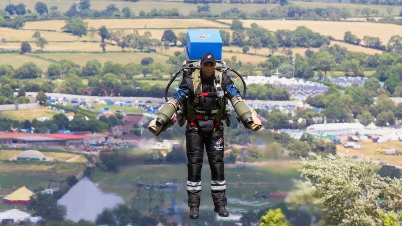 Entregador veste jetpack e literalmente voa com pizzas até clientes no Festival de Glastonbury, no Reino Unido, enquanto a Domino’s usa traje a jato desenvolvido pela Gravity Industries para