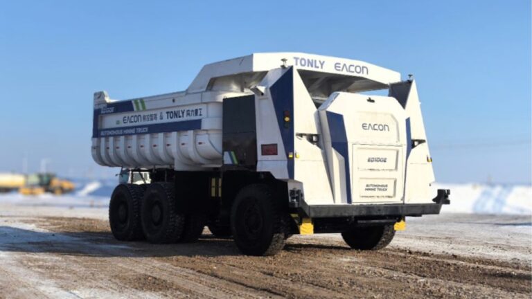Caminhão elétrico autônomo EQ100E branco e azul, sem cabine, em terreno de mineração parcialmente nevado