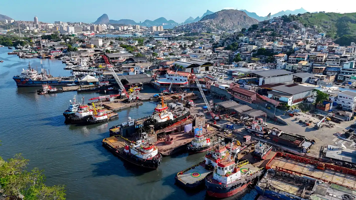 Vista aérea da base da Camorim em Niterói com rebocadores atracados e galpões do estaleiro