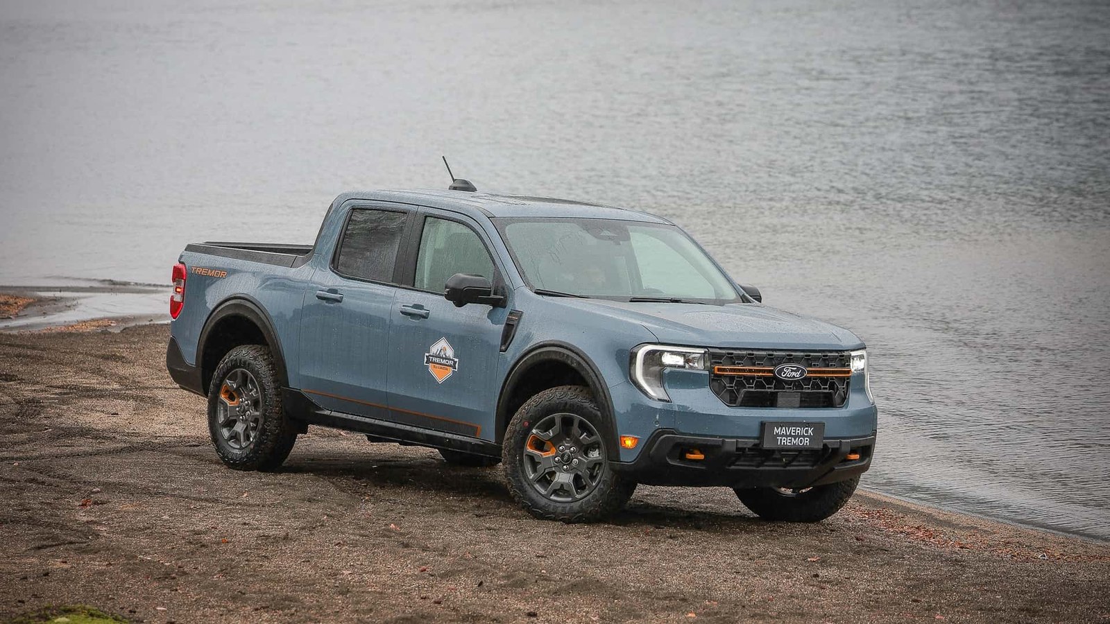 Ford Maverick Tremor azul parada em margem de terra diante de um lago.